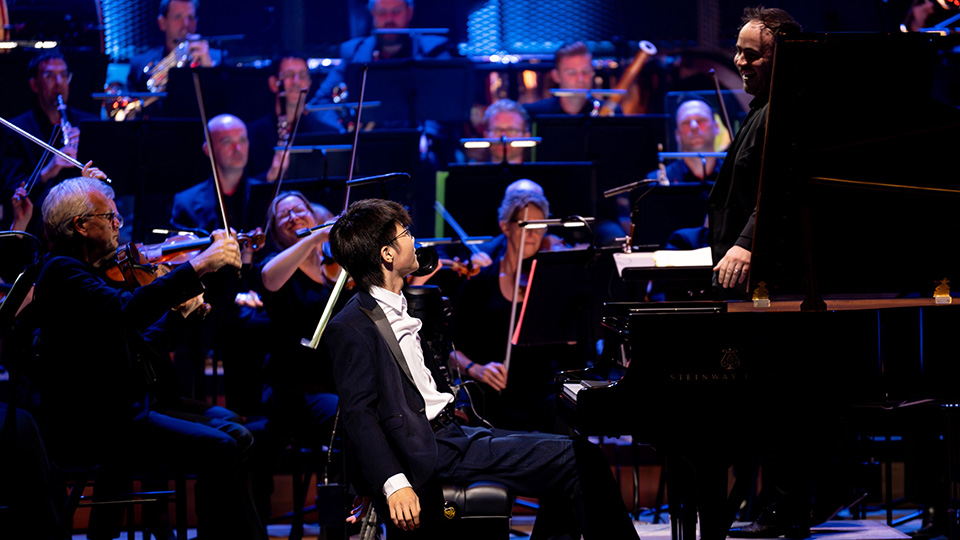  A male pianist in a suit with an orchestra 